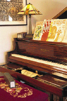 With a grand piano—decked with 1890s-vintage sheet music—and a Wurlitzer pipe organ in the basement, Thom and Dennis have imprinted the home with their love for music. An Ampico reproducing roll player increases the charm of the Knabe grand piano. The artwork hanging behind the piano is the work of Dennis’s brother, artist Maloy Fisher.